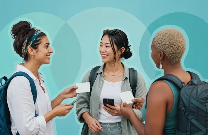 Three women travelers comparing blank membership cards and phones on a turquoise background